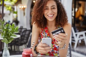 concept-banque-commerce-electronique-internet-heureuse-jeune-femme-souriante-coiffure-afro-utilise-telephone-portable-moderne-carte-credit-pour-achats-ligne